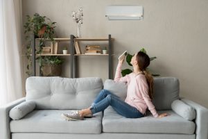 woman-with-remote-turning-on-ductless-air-handler-in-her-living-room