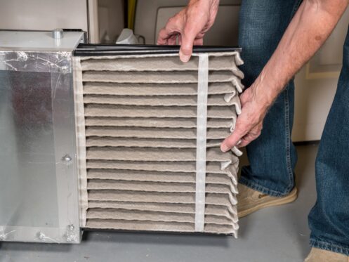 man changing a folded dirty air filter in a furnace