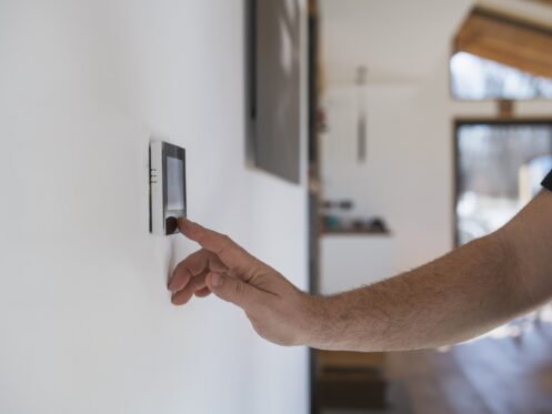 Man at home adjusting a smart thermostat