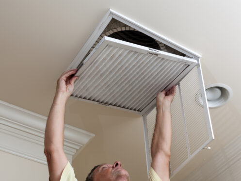 Senior man opening air conditioning filter in ceiling